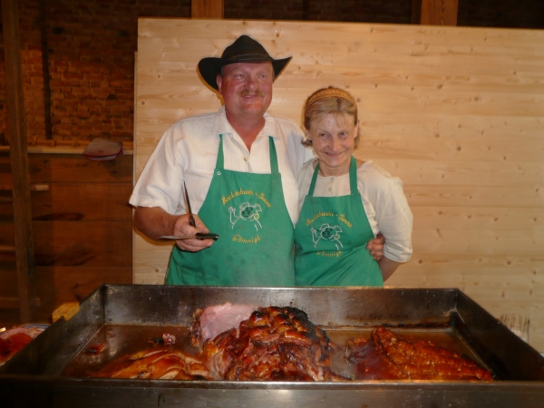 Ein mann und eine Frau stehen vor einer großen Pfanne mit Backschwein aus der Backschwein-Tenne Gömnigk